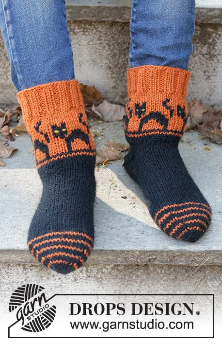 Children 47-29 Spooky Sunset Socks by DROPS Design — Calcetines: 24/25, 26/28, 29/31, 32/34, 35/37, 38/40 y 41/43; pie: 15, 17, 18, 20, 22, 24 y 26 cm. También agujas de doble punta de 2,5 mm y restos amarillos para los ojos. Se incluye un ovillo completo de mostaza oscuro 52 para los ojos amarillos; puede diferir del tono de las fotos. — 1