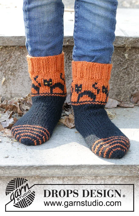 Children 47-29 Spooky Sunset Socks by DROPS Design — Calcetines: 24/25, 26/28, 29/31, 32/34, 35/37, 38/40 y 41/43; pie: 15, 17, 18, 20, 22, 24 y 26 cm. También agujas de doble punta de 2,5 mm y restos amarillos para los ojos. Se incluye un ovillo completo de mostaza oscuro 52 para los ojos amarillos; puede diferir del tono de las fotos. — 2