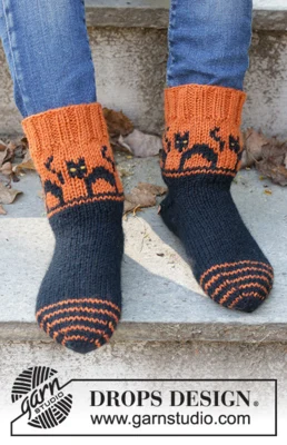 Children 47-29 Spooky Sunset Socks by DROPS Design — Calcetines: 24/25, 26/28, 29/31, 32/34, 35/37, 38/40 y 41/43; pie: 15, 17, 18, 20, 22, 24 y 26 cm. También agujas de doble punta de 2,5 mm y restos amarillos para los ojos. Se incluye un ovillo completo de mostaza oscuro 52 para los ojos amarillos; puede diferir del tono de las fotos. — 1